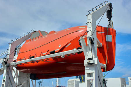 Orange bright lifeboat on the ferry, firmly installed. A rescue boat and a quick launch mechanism. Marine deck equipment.の写真素材