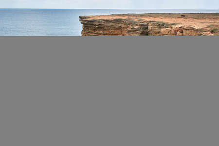 Yellow rocky seashore, cliff. Blue deep calm sea. Calm blue sky. The western part of the Crimea, Cape Tarkhankut. Beautiful natural landscape. Natural stone pattern.の写真素材