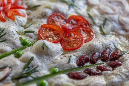 Cooking Focaccia. Raw focaccia creatively decorated with vegetables on parchment paper. Sourdough doughの写真素材