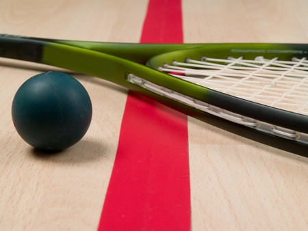 Squash racket and ball next to a red lineの写真素材