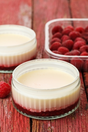 Lemon possets with raspberries on a red wooden backgroundの写真素材