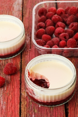 Lemon possets with raspberries on a red wooden backgroundの写真素材