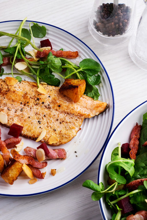 Pan-fried trout with bacon, beetroot and almonds saladの写真素材
