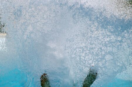 A girl in a water Park has rolled down a slide and the spray is flyingの写真素材