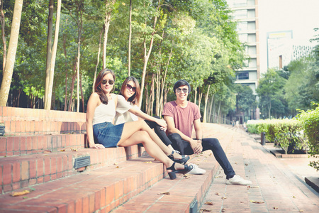 Friends hanging out together while sitting on steps in a parkの写真素材