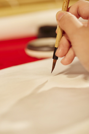 Hand writing Chinese calligraphy with a brush on a sheet of paperの写真素材