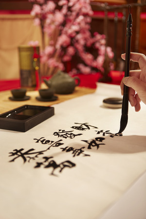 Hand writing Chinese calligraphy with a brush on a sheet of paperの写真素材