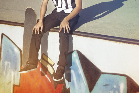 Young man sitting beside a skateboard at a skate parkの写真素材