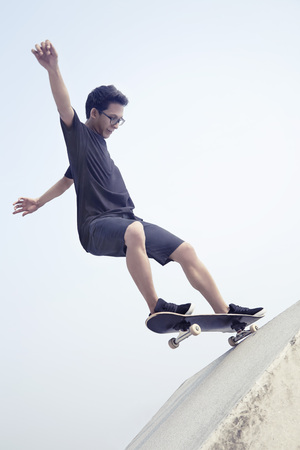 Young man doing skateboarding trick at a skate parkの写真素材