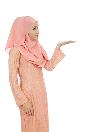 Woman in traditional Baju Melayu with hand open to present somethingの写真素材