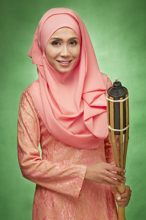 Woman in traditional Baju Kurung holding an oil torchの写真素材