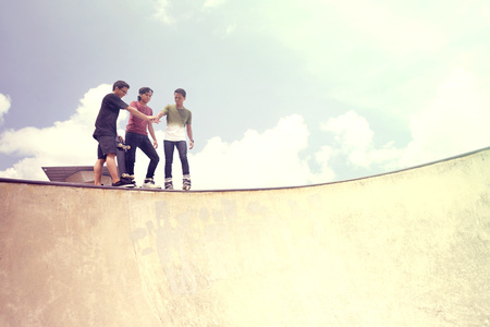 Young men cheering on the edge of ramp at a skate parkの写真素材