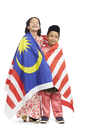 Boy and girl in traditional Malay clothes with Malaysian country flag wrapped around themの写真素材