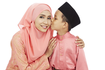 Son kissing mother on the cheek, both in traditional Malay clothesの写真素材