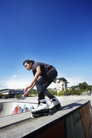 Young man doing inline skating tricks at a skate parkの写真素材