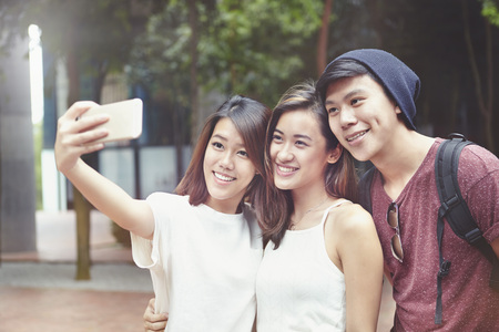 Friends taking selfie together at a parkの写真素材