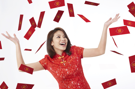 Young woman standing under falling red envelopesの写真素材