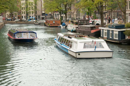 Tourist boats passing by in ana Amsterdam canal.のeditorial素材