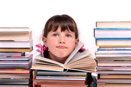 Portrait of cute girl sitting among stacks of books isolated on white backgroundの写真素材