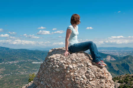 Young girl sitting on an edge of a cliff, Spainの写真素材