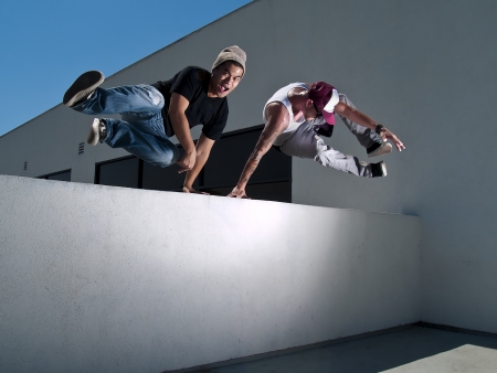 two free-runners jumping over a wallの写真素材