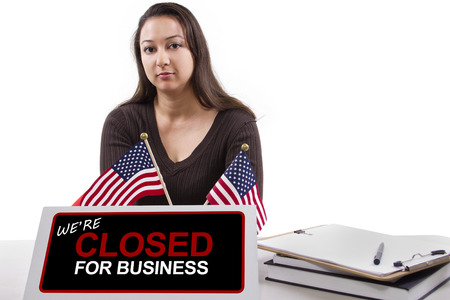 woman with a desk sign showing closed for businessの写真素材