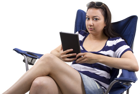 young female with tablet and sitting on a beach chairの写真素材
