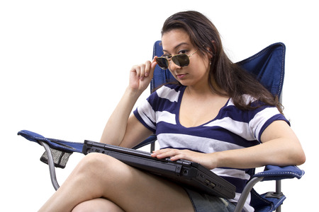 woman on vacation with laptop sitting on a beach chairの写真素材