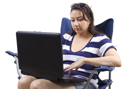 woman on vacation with laptop sitting on a beach chairの写真素材