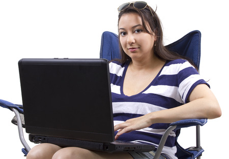 woman on vacation with laptop sitting on a beach chairの写真素材