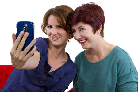 two women taking self portraits with a cell phoneの写真素材