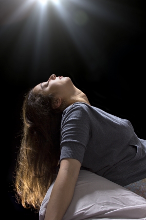 creepy glowing orb hovering over a woman sleeping in bedの写真素材