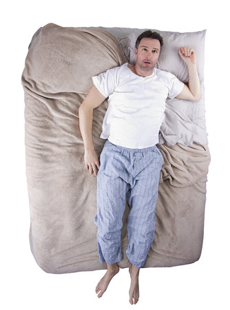 top view of sleep deprived man on a bedの写真素材