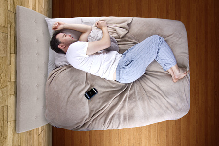 man snoozing modern cell phone alarm clockの写真素材