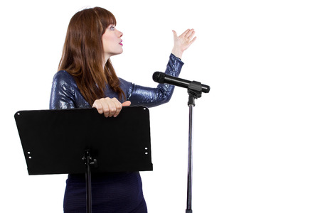 girl in shiny dress speaking on a microphone in a podium on white backgroundの写真素材