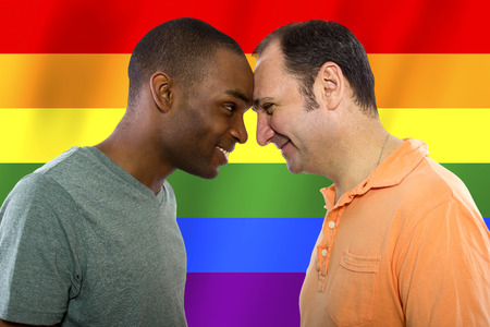 same-sex homosexual couple with a rainbow gay pride flag in the backgroundの写真素材