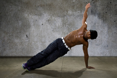 Man demonstrating core balance exercises or yoga on urban background