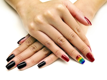 Symbolic LGBTQ pride rainbow nail art manicure on females holding handsの写真素材