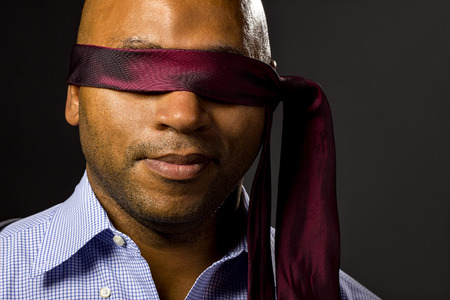 Black businessman blindfolded to represent corporate uncertaintyの写真素材