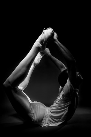 Classical ballet dancer warming up with stretches in black and whiteの写真素材