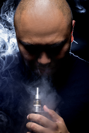 Man with concealed identity smoking a controversial vape is a health risk