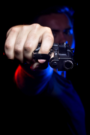 Officer or criminal holding a gun lit with police lightsの写真素材