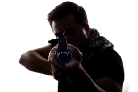 Silhouette of a model posing as a military soldier with a rifle and shemagh scarfの写真素材