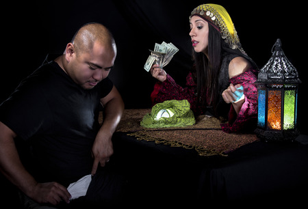 Female fortune teller or con artist swindling money from a male customer via fraudの写真素材