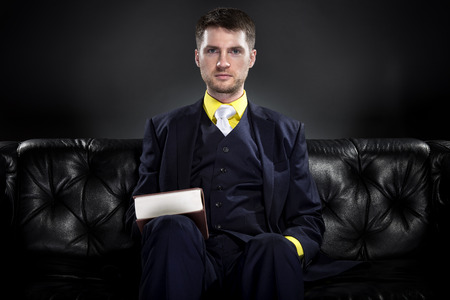 Educated student or businessman with a book wearing a fashionable and stylish classic suit.  He...