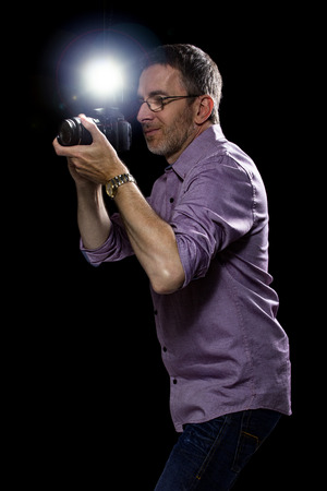 Male paparazzi or editorial photographer journalist using a speedlight flash strobe in the darkの写真素材