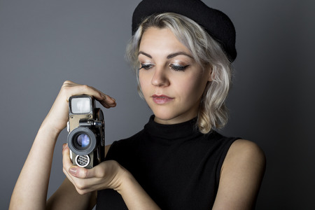Woman holding a vintage video camera posing as a director, filmmaker, or cinematographer in the movie industry.  The image depicts creative arts.の写真素材