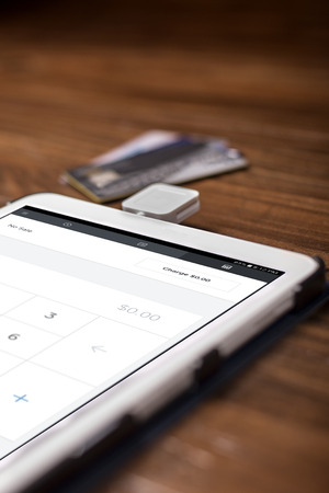 Credit card payment on a swipe or chip reader app on a tablet used by small or online businesses.  The electronic device is used as a modern cash register or for banking.の写真素材