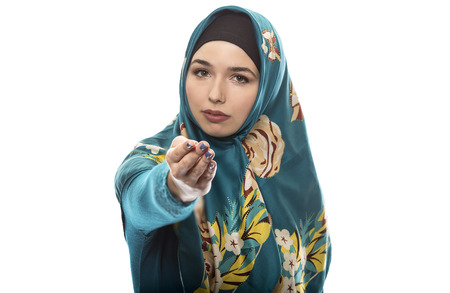 Female wearing a hijab, conservative fashion for muslims, middle east and eastern european culture.  She is isolated on a white background and pointing forwardの写真素材