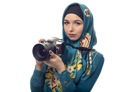 Female photographer wearing a hijab.  She is either a hobbyist or a journalist.  The headscarf is associated with muslims and east european or middle eastern culture.  she is holding a camera.の写真素材